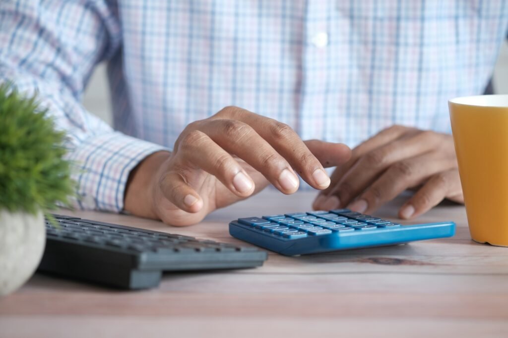 Pessoa analisando se vale a pena pagar INSS em atraso com documentos e calculadora sobre a mesa